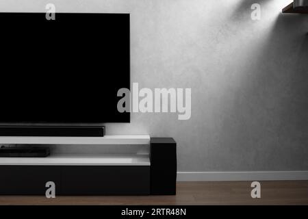 Part of a modern living room interior with a TV on a gray wall, Hi-Fi appliances, a soundbar, a gray wardrobe, copy space. Interior details. Flat TV Stock Photo