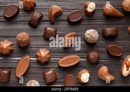 Different chocolate candies on a dark wooden texture background top view. Assorted sweets on the table. Dark and milk chocolates. Chocolate dessert. Stock Photo