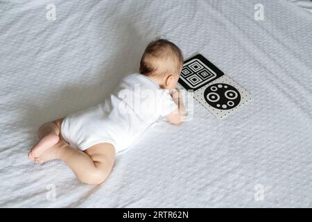 A baby looks at a black and white contrast educational book. Intellectual development of newborns. Developing cards for children. Stock Photo