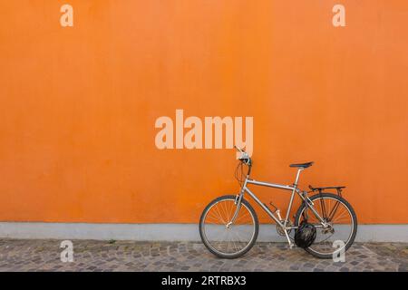 Black bicycle parked next to concrete orange wall. Banner, copy space. High quality photo Stock Photo