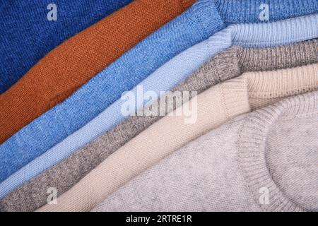 Warm sweaters. Autumn, winter clothes. Metal rack with various sweaters on hangers placed in modern fashion boutique Stock Photo
