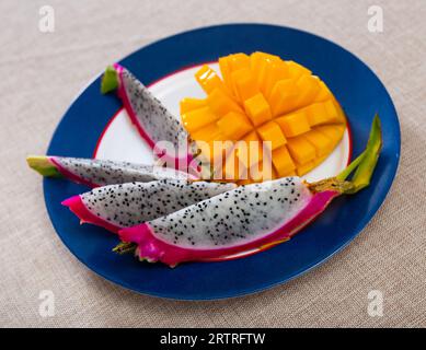 Slices of yellow-orange mango and pink pitaya on plate Stock Photo