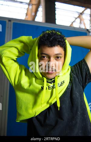 an Asian man with black curly hair posing in a green hoodie at night Stock Photo