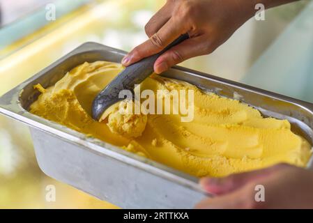 hand scooping a scoop of Passion fruit ice cream into a spoon in fridge Stock Photo