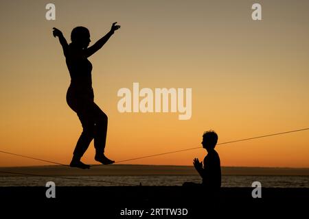 September 14, 2023, Vina del Mar, Valparaiso, Chile: A young woman and a boy practice their slackline walking on a hot winter afternoon at the beach in Vina del Mar, Chile. (Credit Image: © Eduardo Hidalgo/ZUMA Press Wire) EDITORIAL USAGE ONLY! Not for Commercial USAGE! Stock Photo