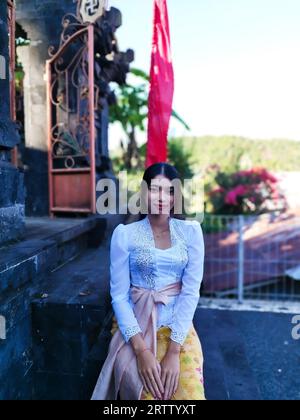 A vertical of a woman in traditional Balinese clothes at the temple Stock Photo