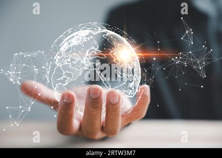 A businessman's hand holds a globe, illustrating seamless connectivity and data flow across global network Stock Photo