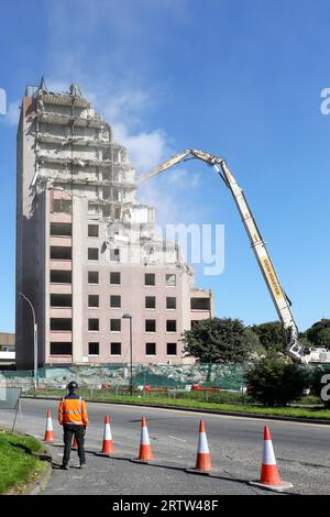 High rise block of flats, Irvine, Ayrshire, Scotland, UK, being demolished by a mechanical crane. Stock Photo