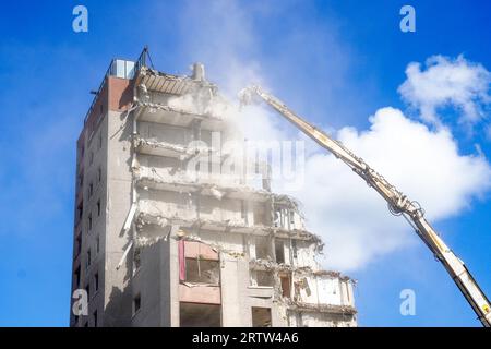 High rise block of flats, Irvine, Ayrshire, Scotland, UK, being demolished by a mechanical crane. Stock Photo