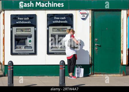 Woman using a cash point machine, for free cash withdrawals, Troon, Scotland, UK Stock Photo