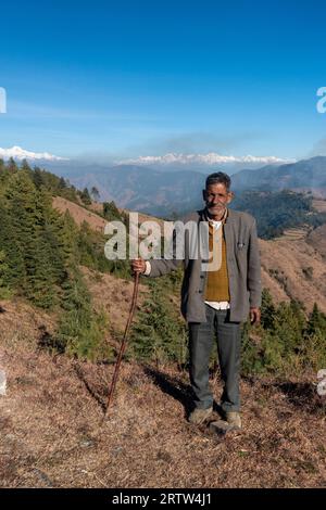 November 30th 2022. Tehri Garhwal, Uttarakhand India. Garhwali local, holding a walking stick, poses in the majestic Himalayas of Garhwal Stock Photo