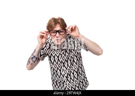 a young caucasian guy with red hair dressed in a shirt squints because of poor eyesight Stock Photo