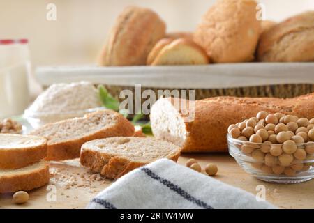 Sliced soy bread and soy beans on a cutting board with flour and bread in a basket in the background. Front view. Stock Photo