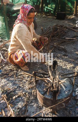 November 30th 2022. Tehri Garhwal, Uttarakhand India. Garhwali woman kindling fire in outdoor cast iron stove, rural Uttarakhand village, winter scene Stock Photo