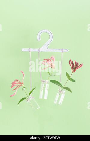 Small glass jars with violet flowers attached to white hanger hands Stock Photo