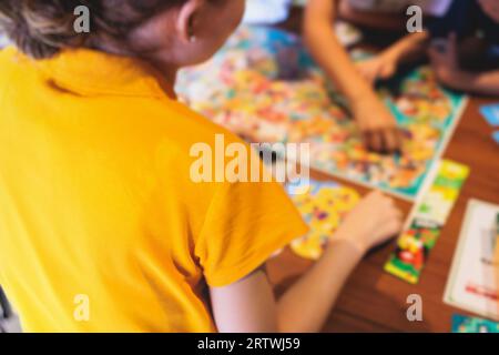 Process of playing board game and having fun with friends and family in room indoors, board game concept, group of kids children play board games at t Stock Photo