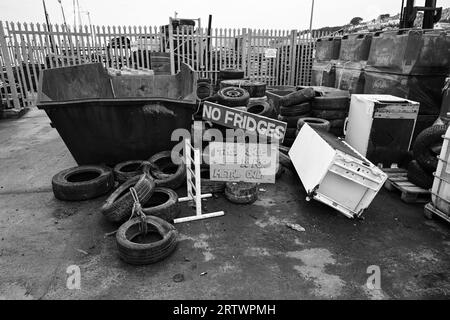 Skip with tyres and sign saying no fridges scrap Stock Photo