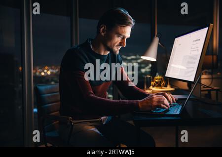 Professional caucasian businessman working late at night in an office, typing on his laptop for a digital marketing project. Creative entrepreneur put Stock Photo
