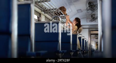 asian woman young stand interior of the train looking at Placing luggage for tourism backpacker. concept transport lifestyle active journey and travel Stock Photo