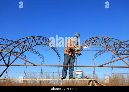 LUANNAN COUNTY, China - December 1, 2021: farmers weld steel skeleton greenhouses in farmland, North China Stock Photo