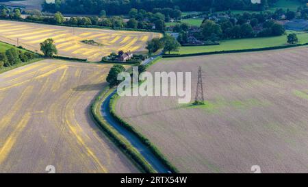 Aerial landscape shot of the countryside near the village of west Compton in West Sussex. Electricity pylons crossing the land. Road in middle of shot Stock Photo