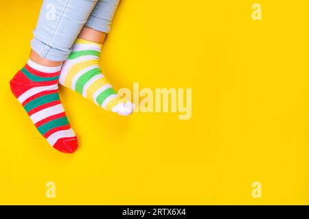 Odd Socks Day, Lonely Sock Day.  Anti-Bullying Week, Down syndrome awareness. Child legs wearing different pair of mismatched socks on high-colored ba Stock Photo