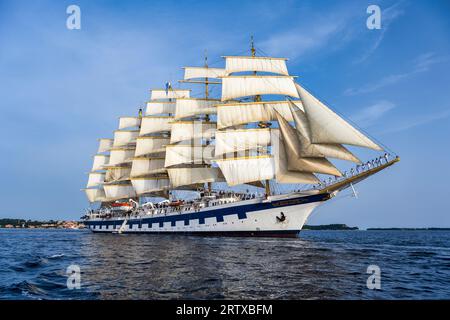 Tall ship Royal Clipper of Star Clippers under full sail, with crew lined up on bow sprit, departing Rovinj on the Istrian Peninsula of Croatia Stock Photo