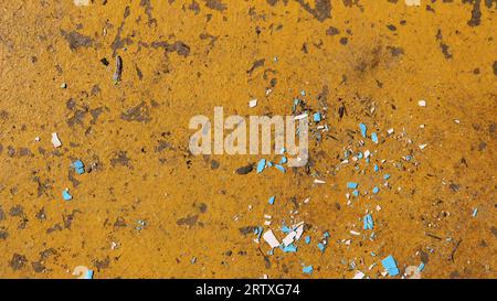 flaky surface of bright orange color interspersed with sharp blue spots as a textural abstraction, abstract background with aged texture Stock Photo