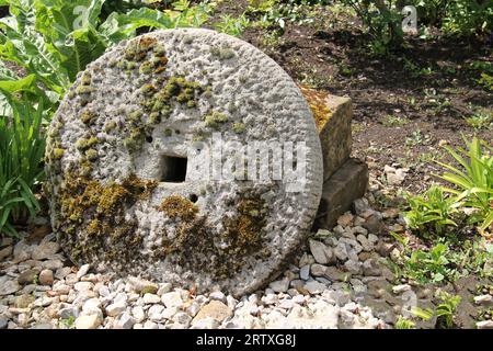An Ornamental Moss Covered Stone Grinding Wheel. Stock Photo
