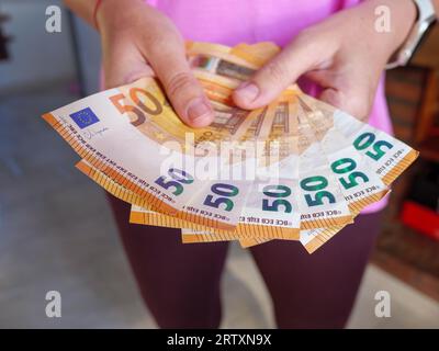 Close up of hands holding out 50 Euro banknotes in cash Stock Photo