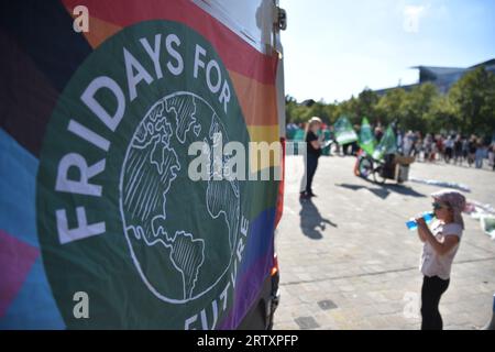 Magdeburg, Germany. 15th Sep, 2023. A rainbow flag with the Fridays for Future logo hangs from the back of a small van. In the background, a female speaker can be seen speaking at the so-called 'climate strike' on Magdeburg's Domplatz. With more than 200 demonstrations and rallies throughout Germany, the climate protection movement Fridays for Future wants to persuade the government this Friday, as part of the global climate strike under the motto #EndFossilFuels, to accelerate the phase-out of coal, oil and gas. Credit: Simon Kremer/dpa/Alamy Live News Stock Photo