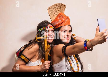 Couple of friendly girls taking a selfie wearing ethnic clothes of African culture. Accessories and typical African fashion. Funny photography for soc Stock Photo