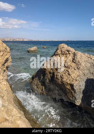 Seascape with a view of the rocky coast, beautiful sea surface, waves crashing on a rocky cliff. A clear sunny day. Stock Photo