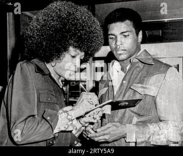 New York, New York  September 9, 1974 Muhammad Ali and Angela Davis exchange autographs when they run into each other at La Guardia Airport. Ali was on his way to Zaire to fight George Foreman, Stock Photo