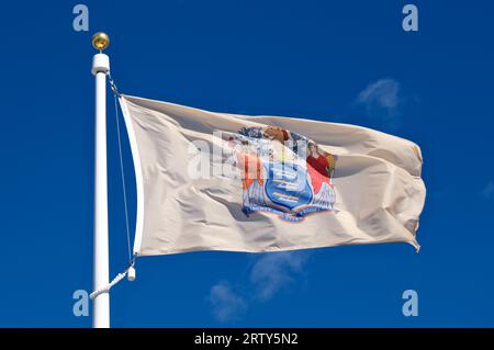 Close up of New Jersey state flag against a blue sky background and white clouds Stock Photo