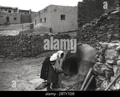 Laguna, New Mexico  c. 1897 A Laguna Native American baking bread in the early morning in her outdoor oven. Stock Photo