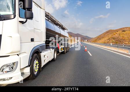 Broken down tanker truck on the highway with cones placed by the highway service to cut off the busy lane. Stock Photo