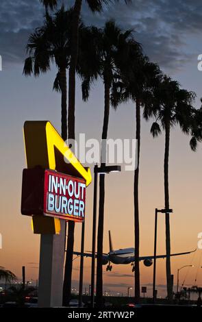 A plane arriving at LAX passes just next to the iconic sign for an In N Out burger restaurant on Sepulveda Blvd, Los Angeles, CA, USA Stock Photo