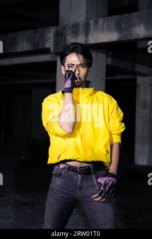 an asian man with a yellow jacket and black hair posing very gallantly in an abandoned building Stock Photo