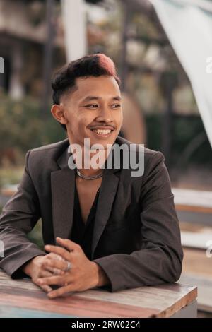 a teenage boy with blond hair poses very funny and cute when wearing a suit during the day Stock Photo