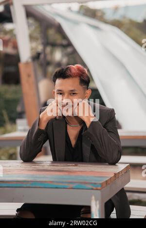a teenage boy with blond hair poses very funny and cute when wearing a suit during the day Stock Photo