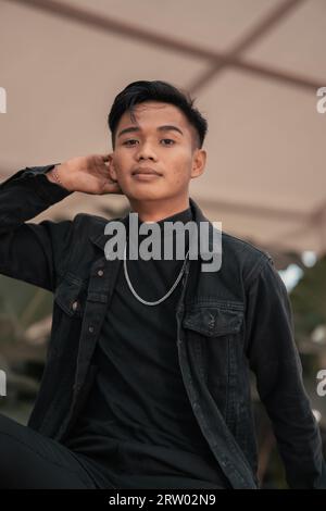 An Asian Man In A Black Denim Jacket And A Chain Necklace Posing