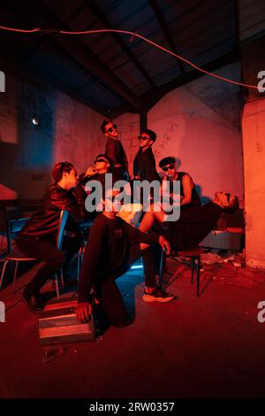 a group of thugs wearing dark clothes and glasses were having fun chatting with their friends in an old building at night Stock Photo