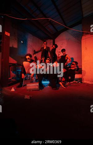 a group of thugs wearing dark clothes and glasses were having fun chatting with their friends in an old building at night Stock Photo