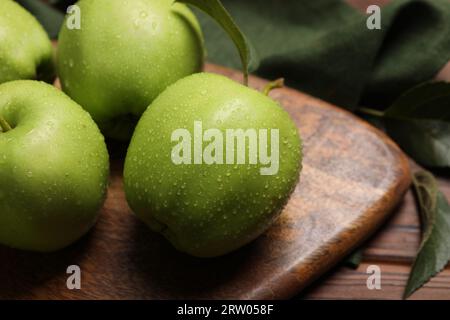 Ripe green apples with leaves and water drops on wooden table, closeup Stock Photo