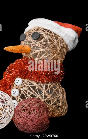 New Year's toy decorative design snowman made of linen thread voluminous with balls next to each other on a black background. Stock Photo