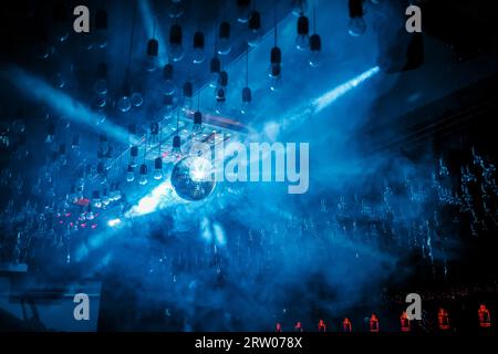 The atmosphere of a nightclub nightlife, a disco, a brilliant glare, a ball in blue smoke. Stock Photo