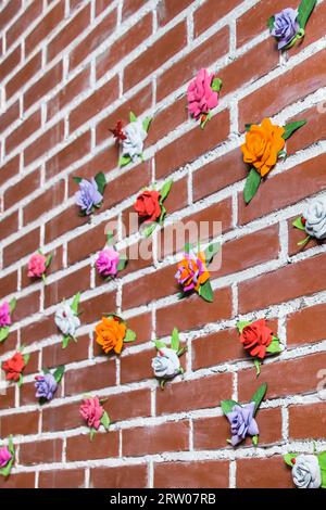 The brick wall is decorated with artificial objects, flowers, multi-colored roses, the interior. Stock Photo