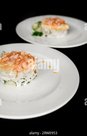 Beautiful serving dish salad under the crooks and garnished with herbs on a 2 two white plate food restaurant on a black background. Stock Photo