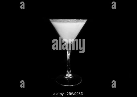 A martini glass with a white alcoholic beverage on an black background. Stock Photo